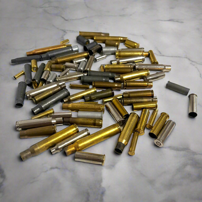 Pile of mixed spent cartridge cases, calibers in brass, nickel, and steel displayed on a marble surface