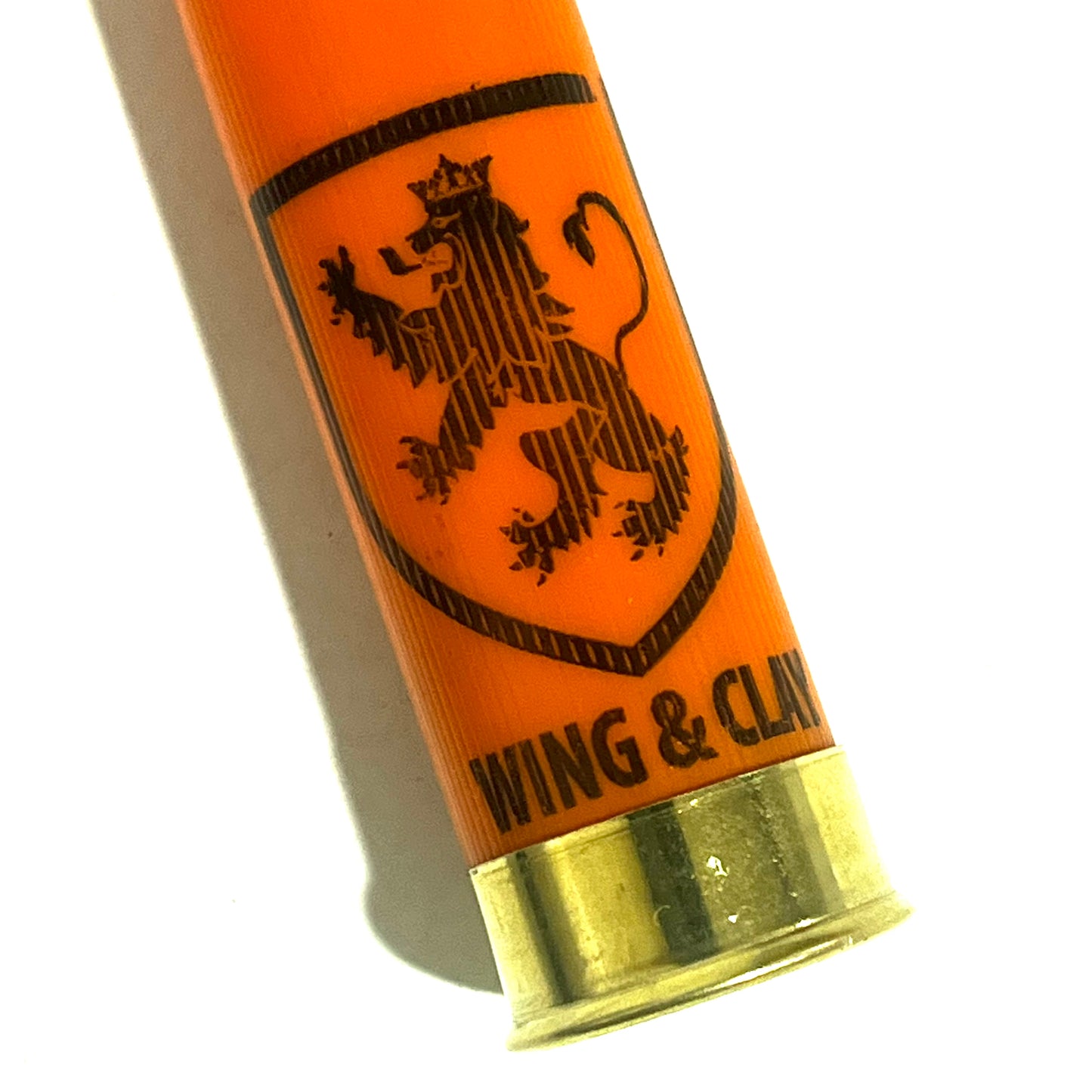 Close-up of an orange Monarch Wing & Clay 12 gauge shotgun shell showing the lion crest logo