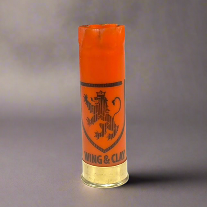 Orange Monarch Wing & Clay 12 gauge shotgun shell with a lion crest logo, standing on a gray background
