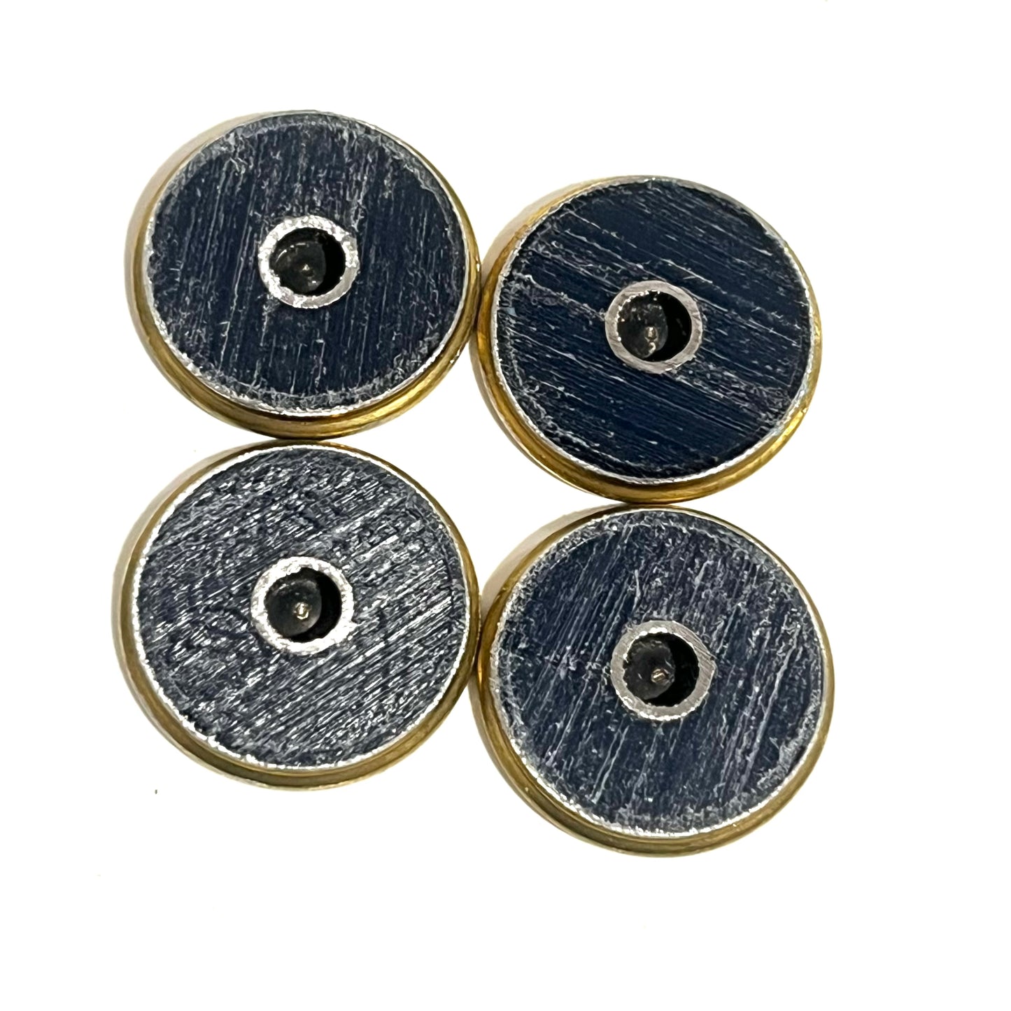 4 shotgun shell slices viewed from the reverse side showing dark blue scratched hulls with drilled holes and brass rims