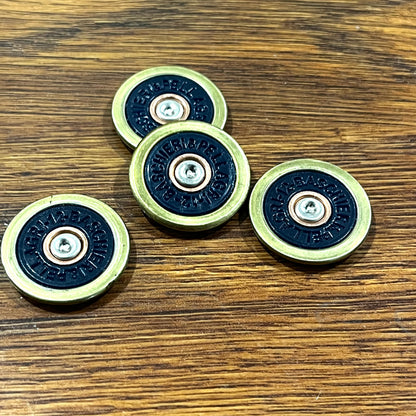 4 navy blue Baschieri & Pellagri 12 gauge shotgun shell slices with brass rims on a wood table