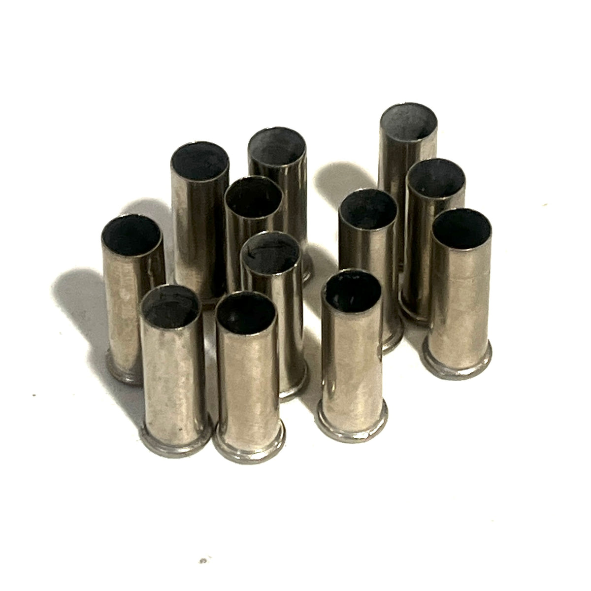 12 nickel 22 caliber empty casings standing upright with open ends up on a white background