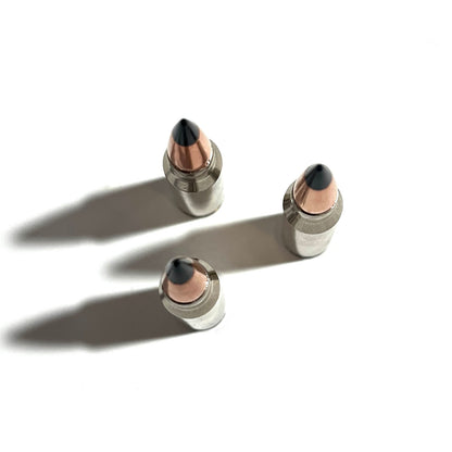 Three nickel .308 dummy casings viewed from above with black tips and long shadows