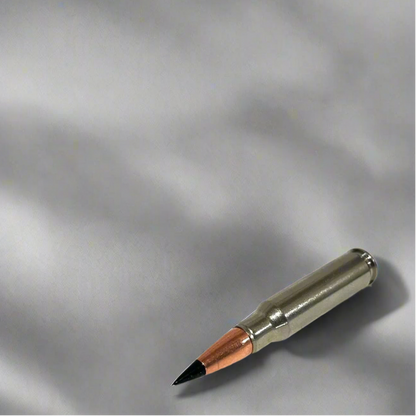 Single nickel .308 dummy round with black tip resting diagonally on a light gray fabric surface