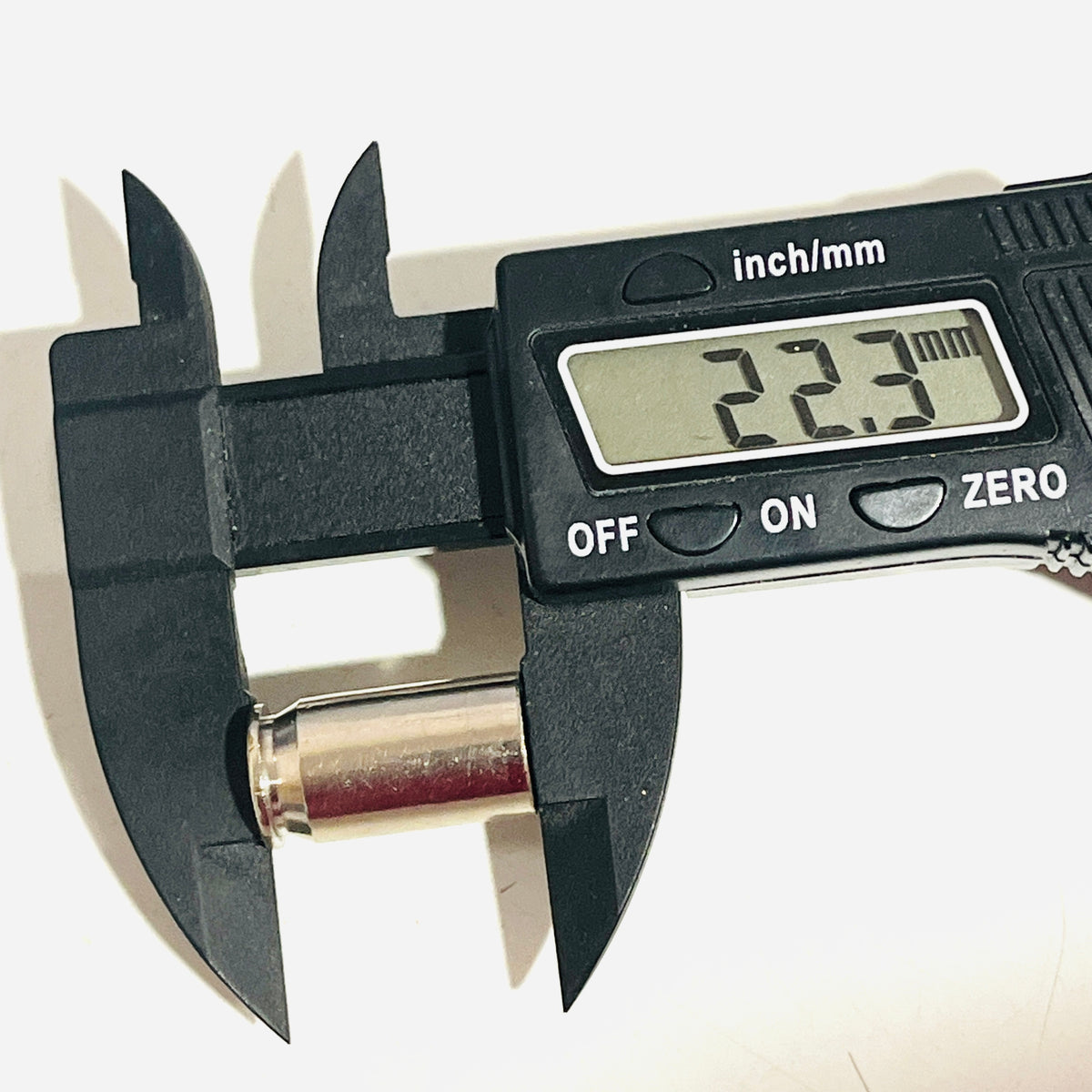 Digital caliper reading 22.3 mm along the full length of an empty nickel 45 ACP casing