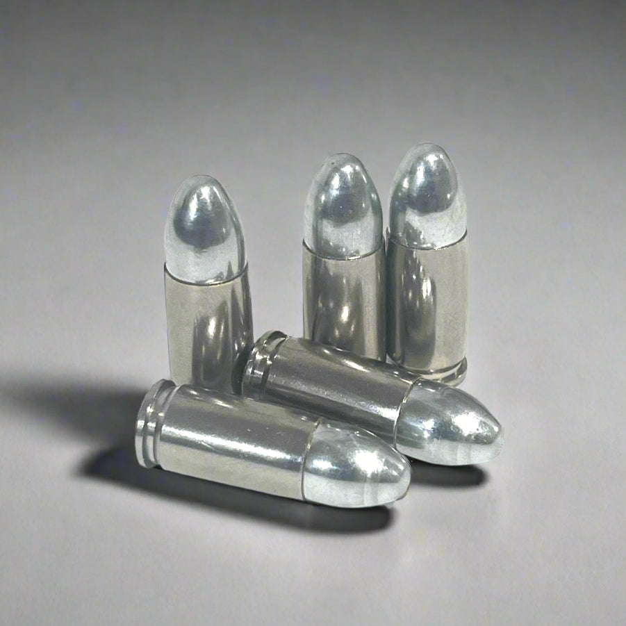 Five nickel 9mm hulls, three standing upright and two crossed in front, on a gray background.