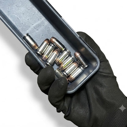 Five nickel snap caps with copper round nose bullets sitting in a tray black gloved hand.