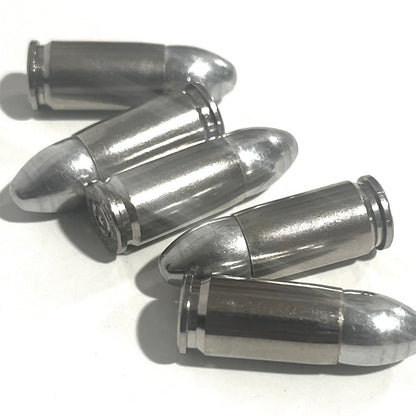 Five nickel 9mm shells fanned out on a white surface, one showing its base rim.