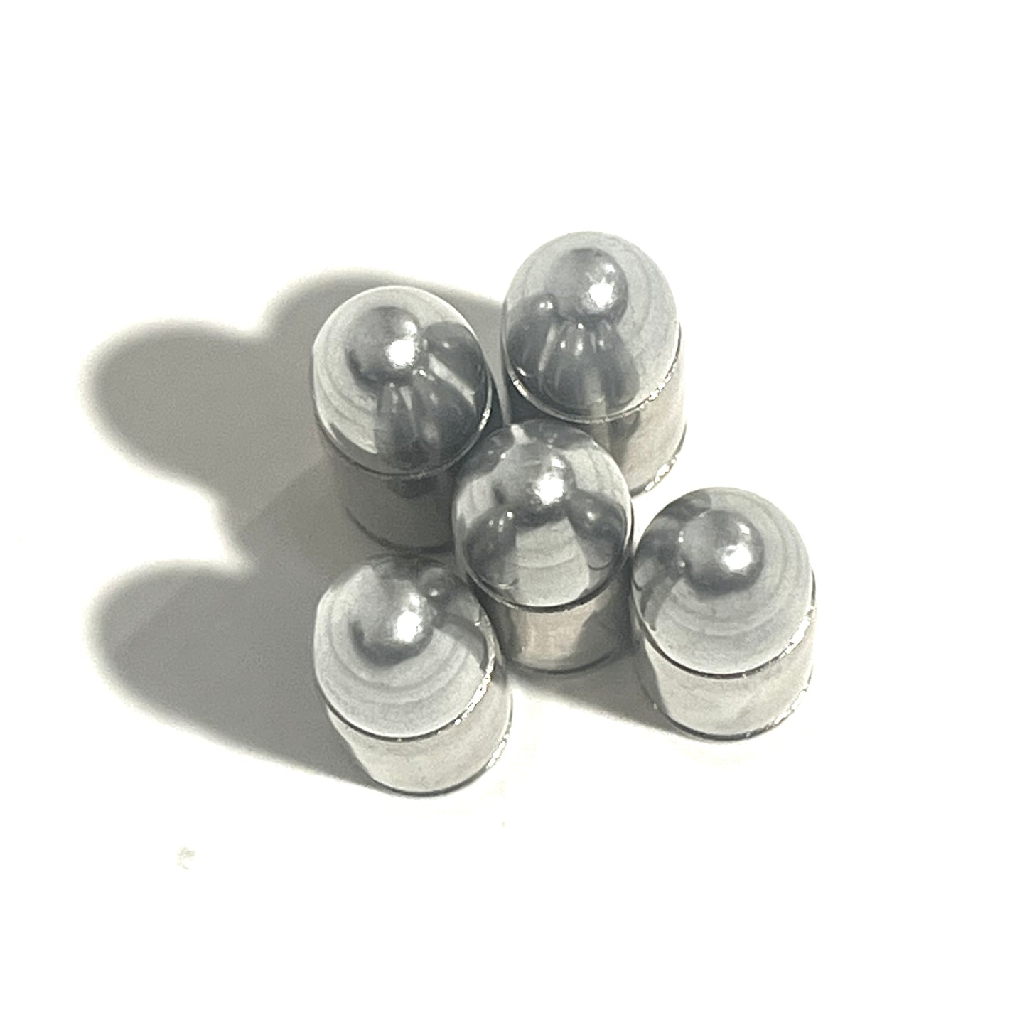 Five nickel 9mm casings viewed from above, showing their rounded bullet tips and shadows.