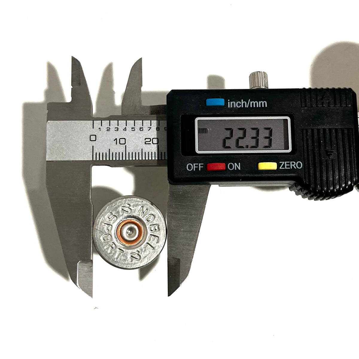 Digital caliper measuring the diameter of a silver Nobel Sport 12 gauge shotgun shell slice at 22.33 mm