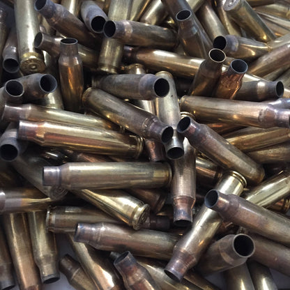 A dense, jumbled pile of uncleaned raw once-fired 5.56 brass rifle casings showing firing tarnish and neck wear.