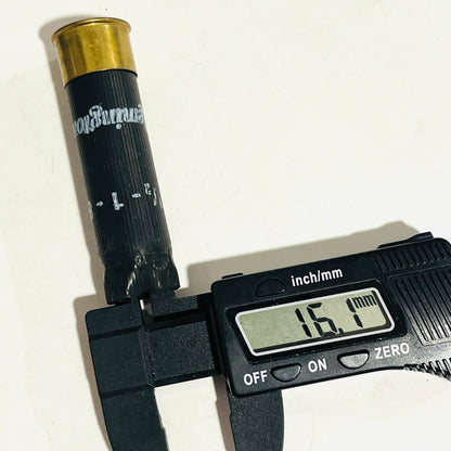 Once-fired black hull standing upright with a digital caliper measuring the crimped case mouth at 16.1 mm