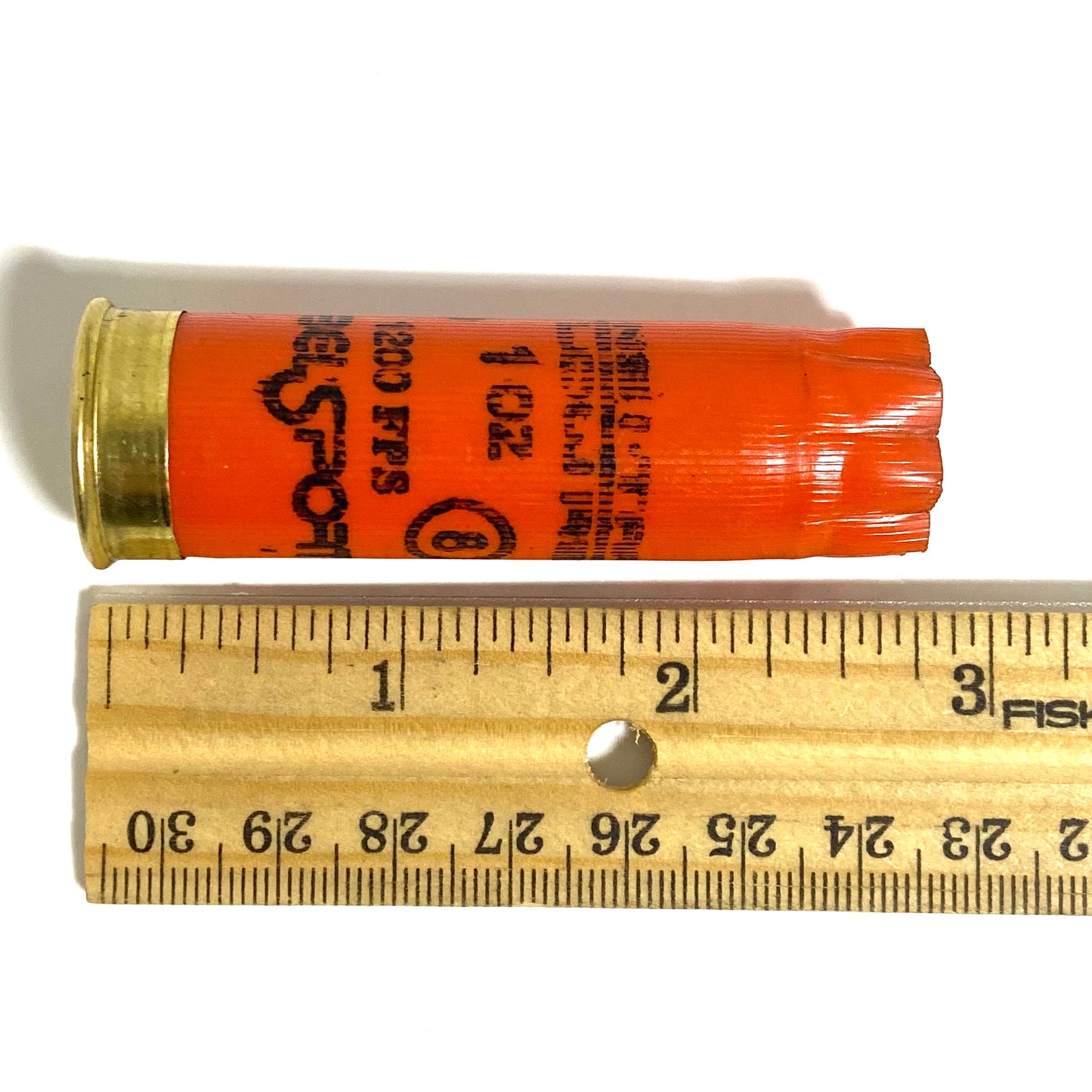 A single orange Nobel Sport shotgun shell measured against a Fiskars ruler showing about 2.75 inches