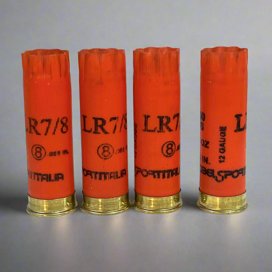 4 orange shotgun shells labeled LR7/8 and 12 gauge standing in a row with brass bases