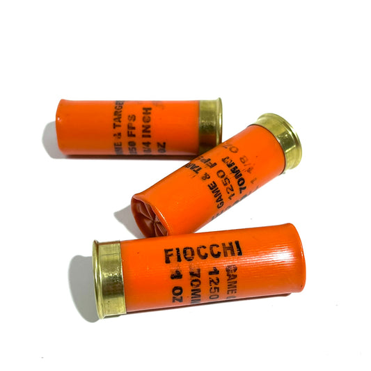 Three spent orange Fiocchi hulls crossed together, showing Game & Target 1250 FPS markings.