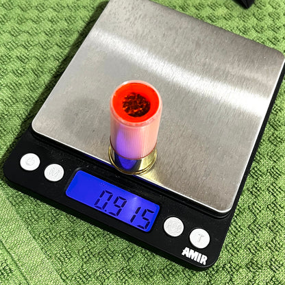 Peach mini shotgun shell with red interior on a digital ounce scale reading 0.915 oz, on green towel