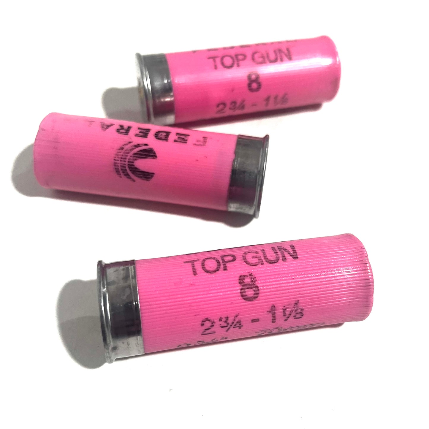 Three pink Federal Top Gun 8 shotgun shells lying on their sides showing 2 3/4 - 1 1/8 headstamp markings