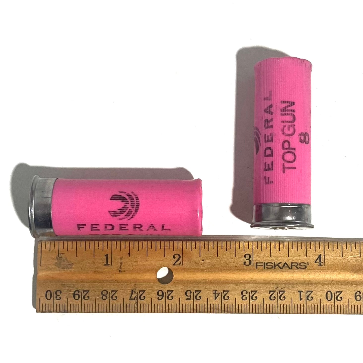 Two pink Federal Top Gun 8 shotgun shells beside a ruler showing a length of about 2.75 inches