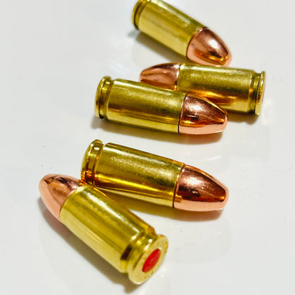 Five spent brass dummy rounds with copper round-nose bullets lying staggered in alternating directions on white