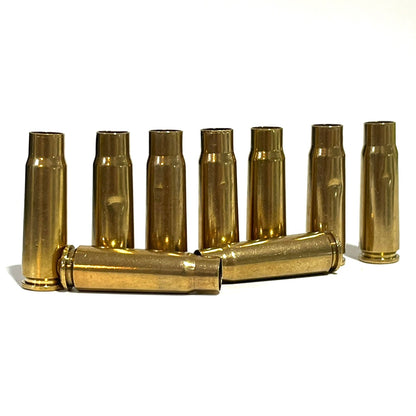 Seven brass cartridges standing upright with two more crossed in front, once-fired and drilled, on white background.