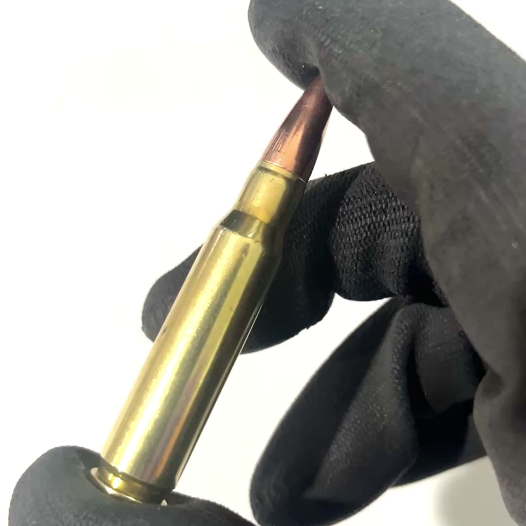 308 once fired dummy prop round for film shake noise test in black gloved hand.