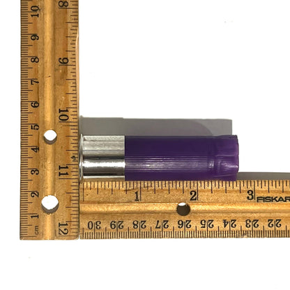 Purple 12 gauge shotgun shell hull measured on a wood ruler at approximately 2.75 inches