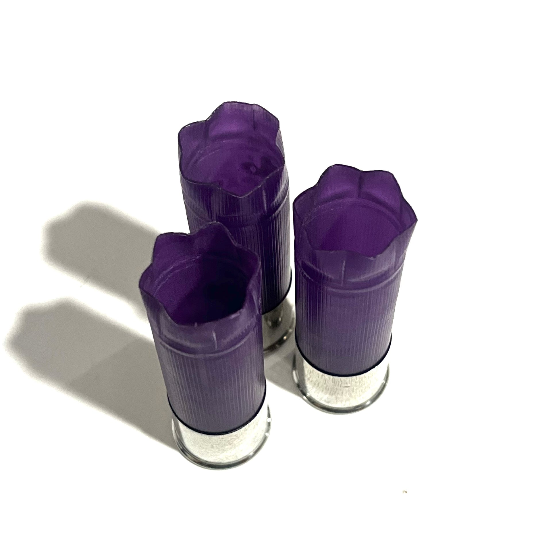 3 purple 12 gauge shotgun shell hulls with silver bases, standing upright with crimped star-fold tops
