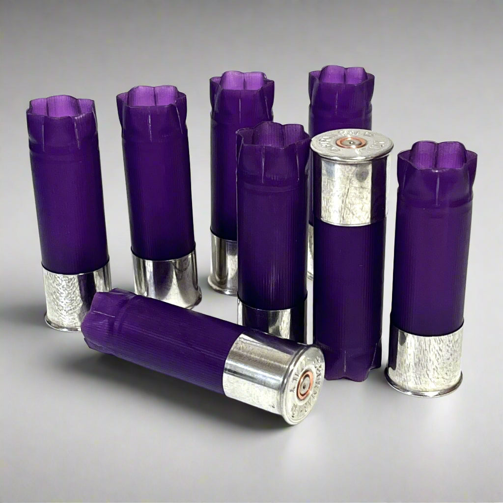8 purple 12 gauge shotgun shell hulls with silver high brass bases, standing and lying on a gray background