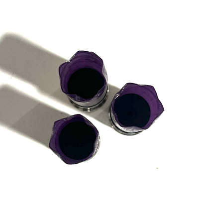 3 purple 12 gauge shotgun shell hulls with silver bases, viewed from above showing crimped star-fold tops