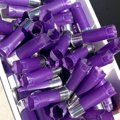 Pile of purple 12 gauge shotgun shell hulls with silver bases in a white bin