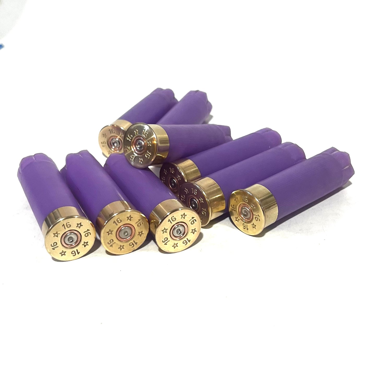 9 purple 16 gauge shotgun shell hulls with brass headstamps marked 16, some standing and some lying down