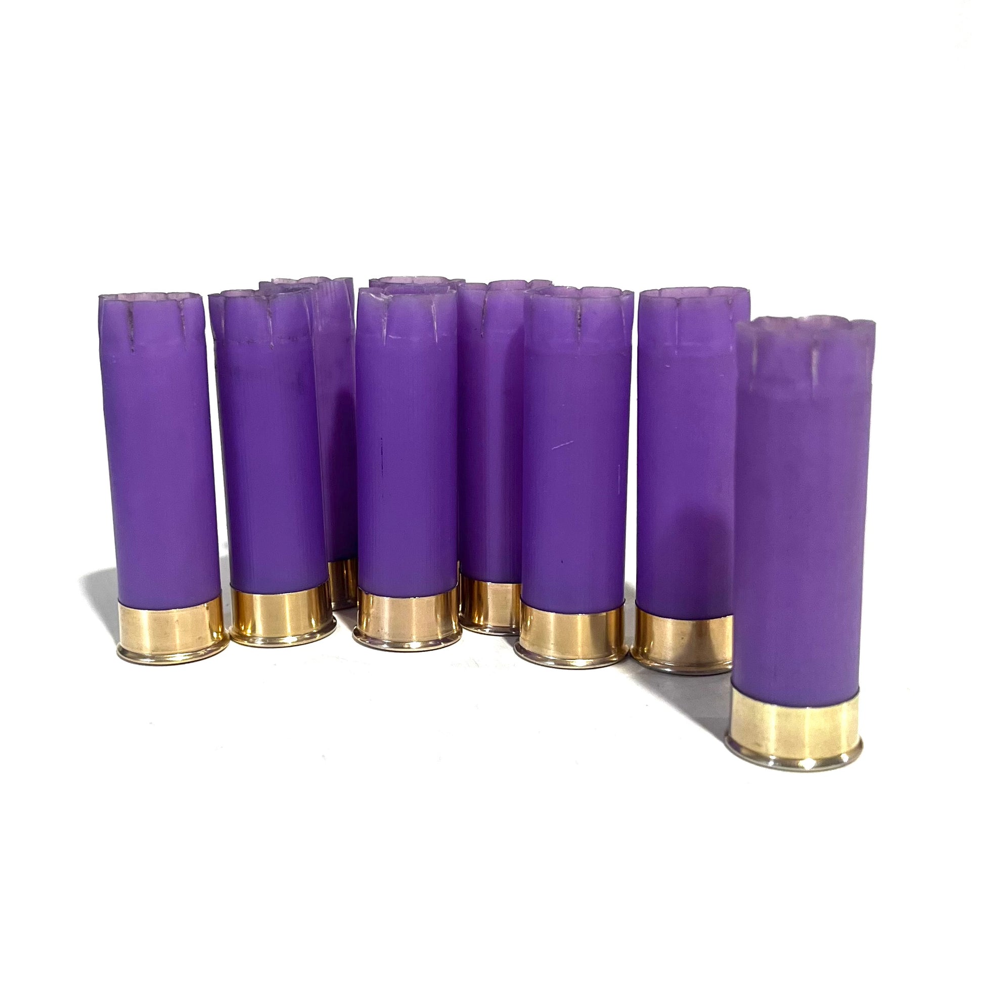 9 purple 16 gauge shotgun shell hulls with brass bases standing upright on a white background
