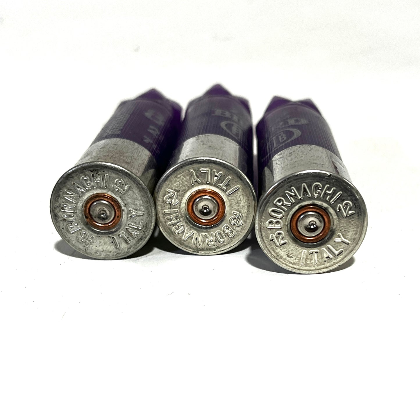 Three purple shotgun shells showing silver Bornaghi Italy headstamps with copper primers