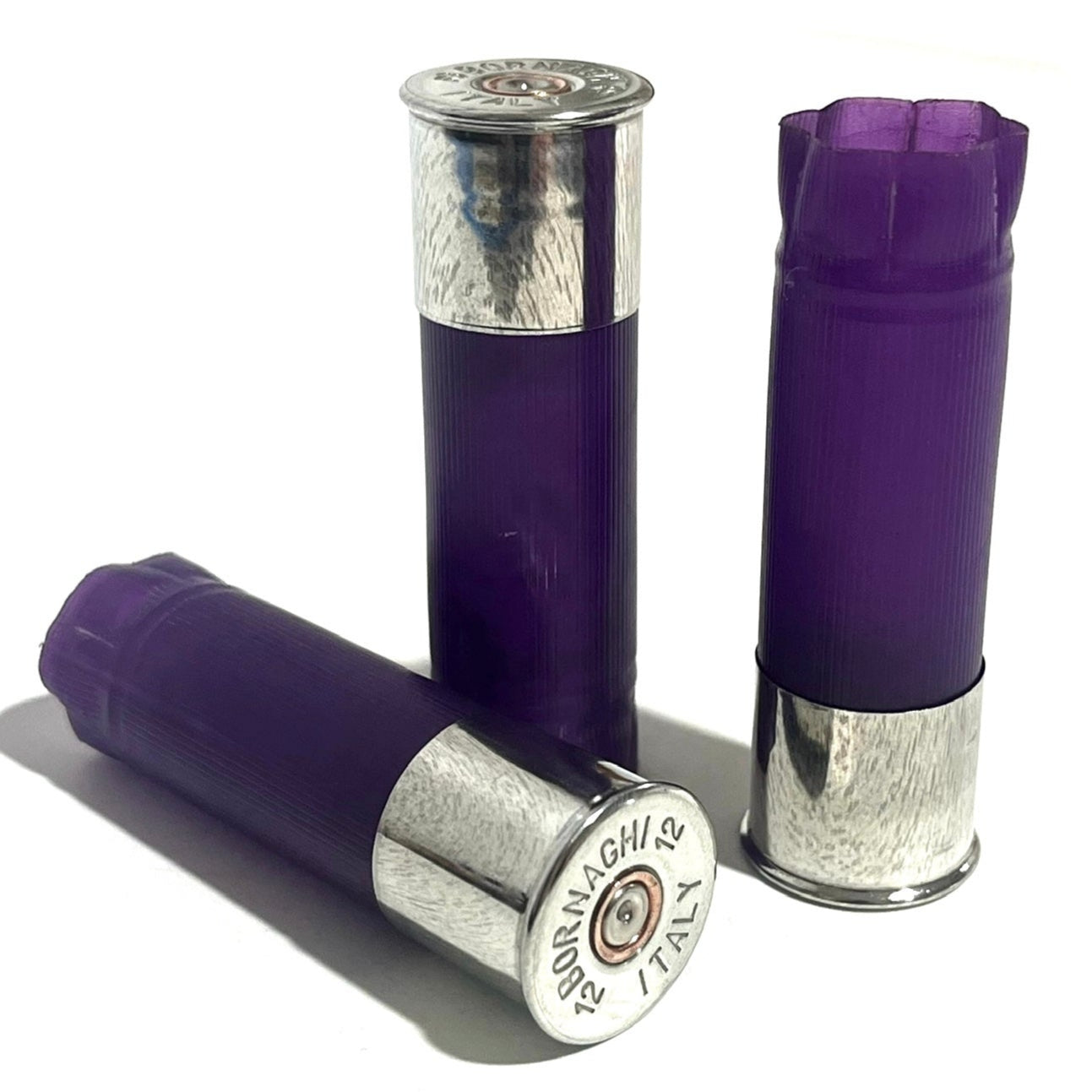 3 purple 12 gauge shotgun shell hulls with silver Bornaghi base caps, standing and lying on a white background
