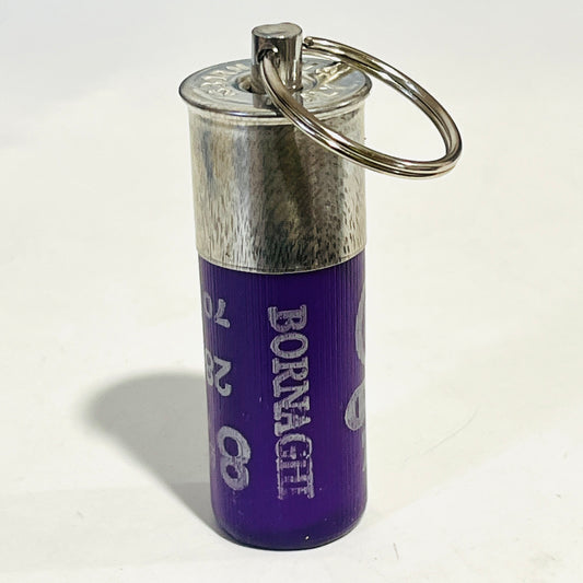 Spent purple Bornaghi shotgun shell keychain standing upright on its crimp end, metal head and split ring on top