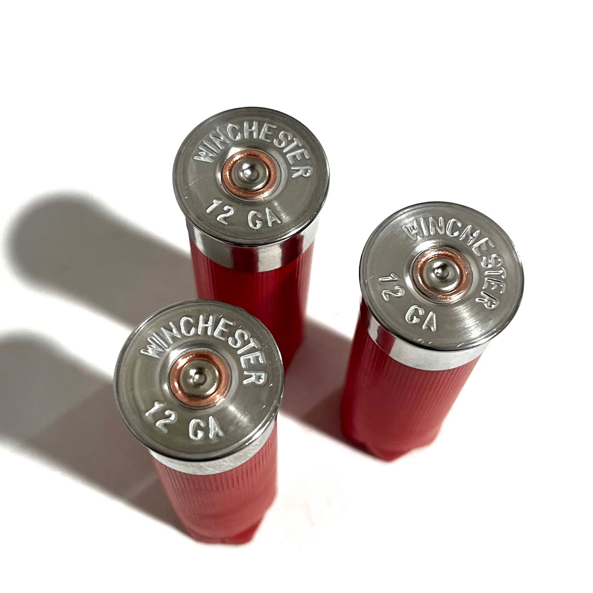 Silver Winchester 12 GA headstamps on the bottoms of three red shotgun shells