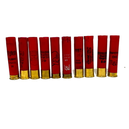 Ten red 28 gauge shotgun shells with gold bottoms from various brands standing in a row