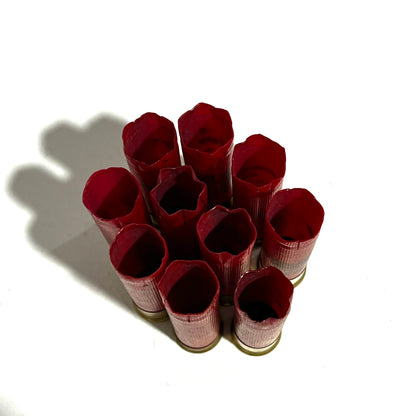 Nine red 28 gauge shotgun shells with gold bottoms viewed from above showing open crimped tops