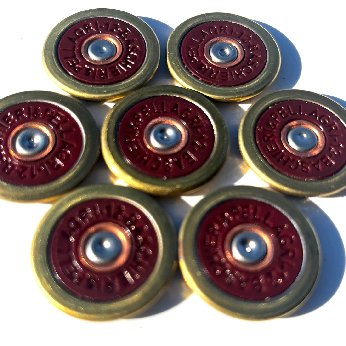 7 Baschieri and Pellagri 12 GA red shotgun shell slices with brass rims arranged closely together