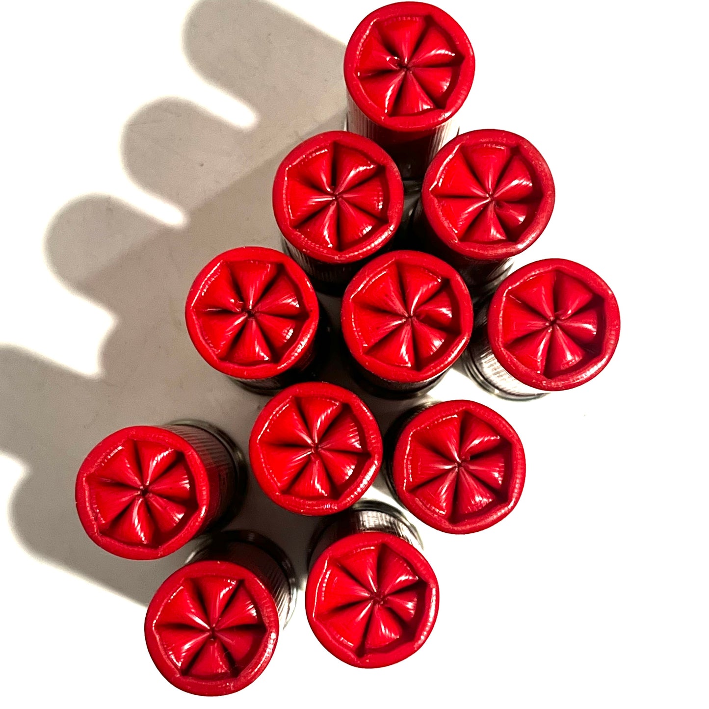 Ten red empty shells bundled together showing star-crimped tops from directly above