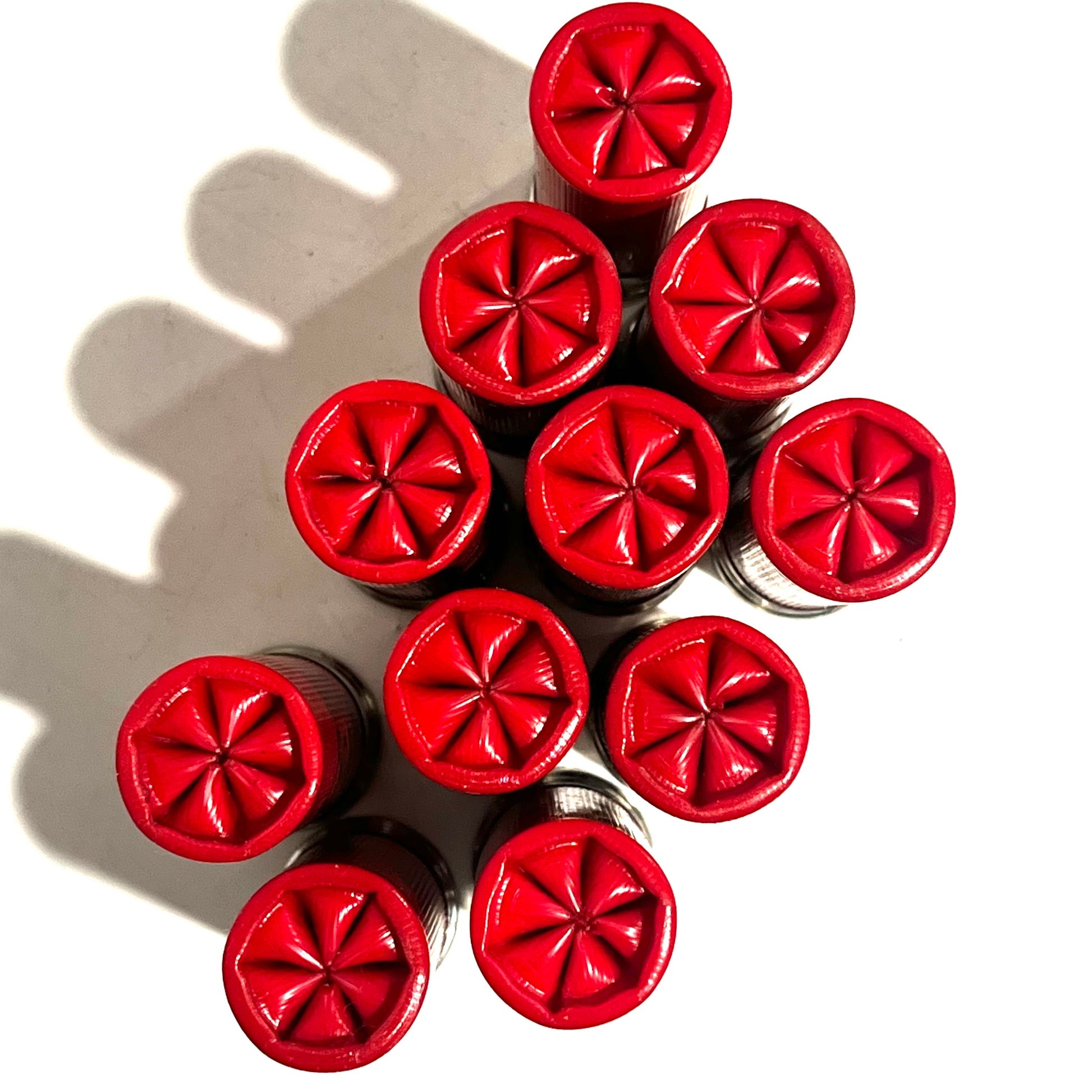 Ten red empty shells bundled together showing star-crimped tops from directly above