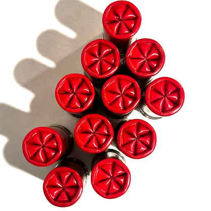 Ten red empty shells bundled together showing star-crimped tops from directly above