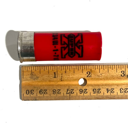 Single red once-fired hull marked '2 3/4 IN' laid against a wooden ruler for length