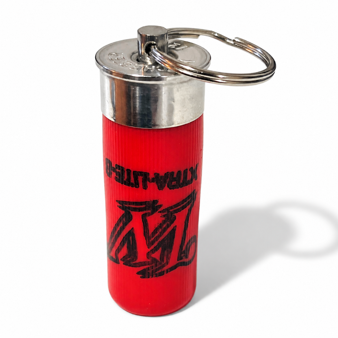 Red once-fired shotgun shell keyring standing upright on white, split ring looped through the steel pin on top