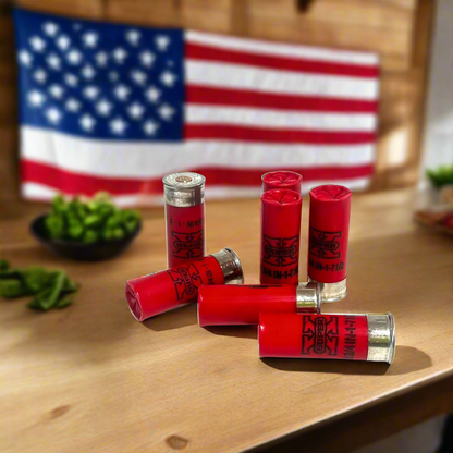 Six red spent shells arranged on a wood table with an American flag and bowl of green vegetables