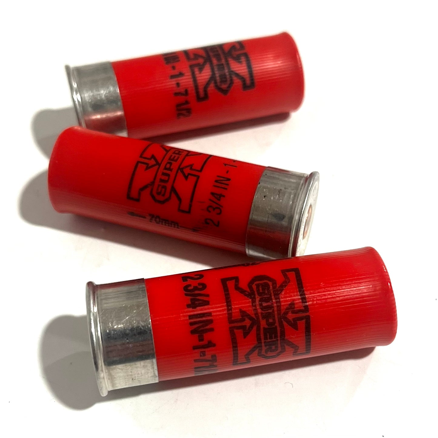Three red used casings lying diagonally with open silver ends and bold logo markings