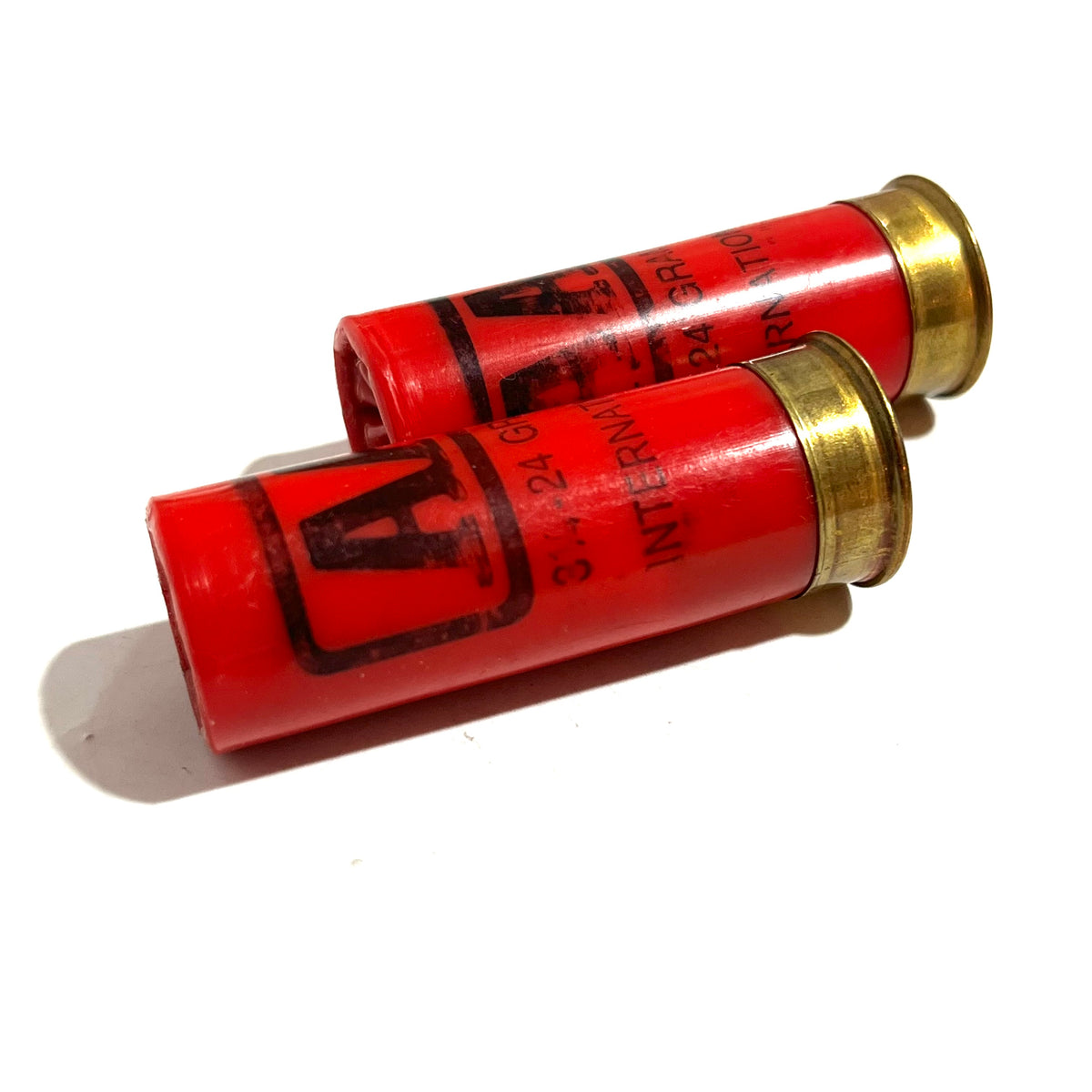 Two red Winchester AA International 12 gauge shotgun dummy rounds laid diagonally showing gold brass bases and hull text