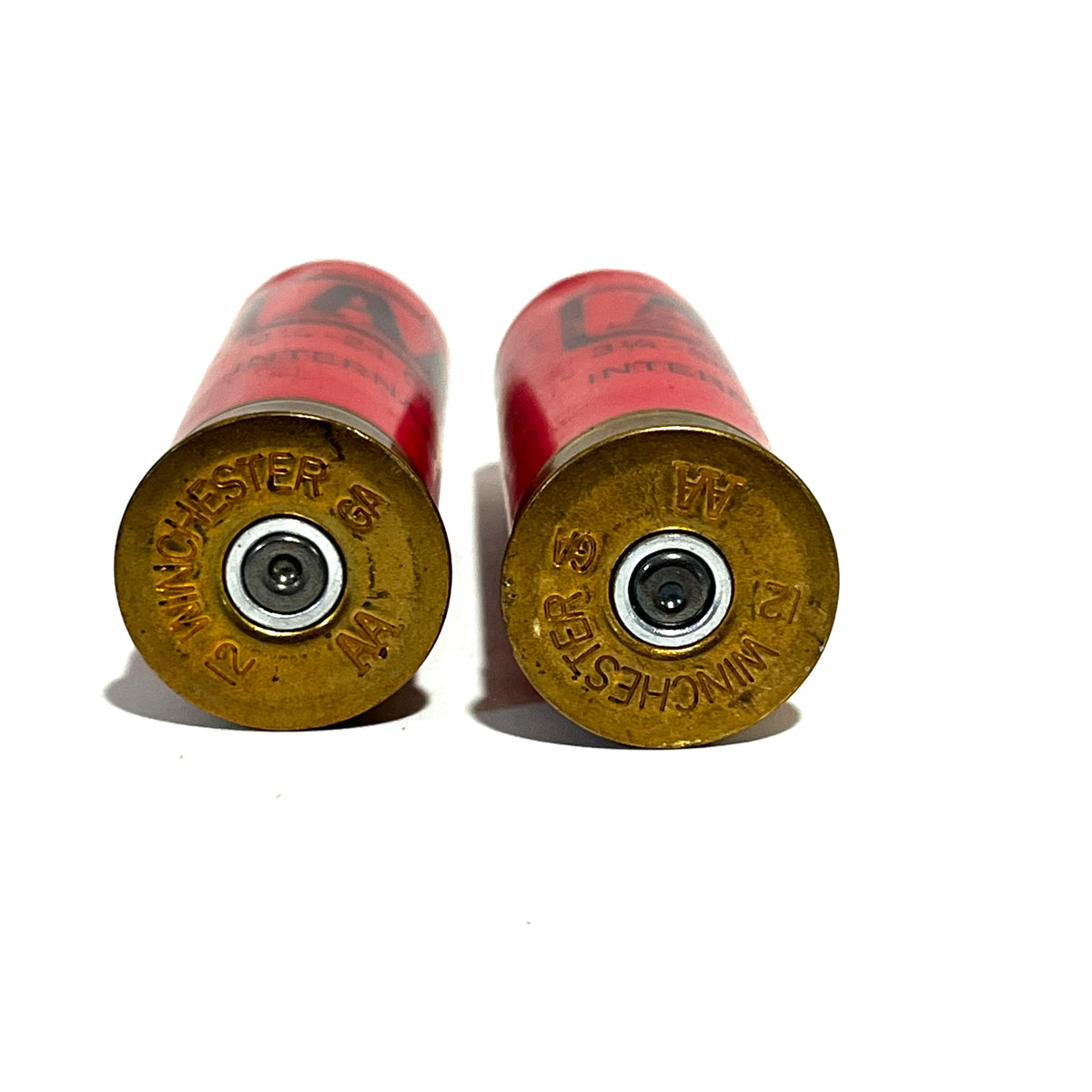 Two red Winchester AA International 12 gauge shotgun dummy round brass bases viewed from below showing Winchester 12 GA headstamps