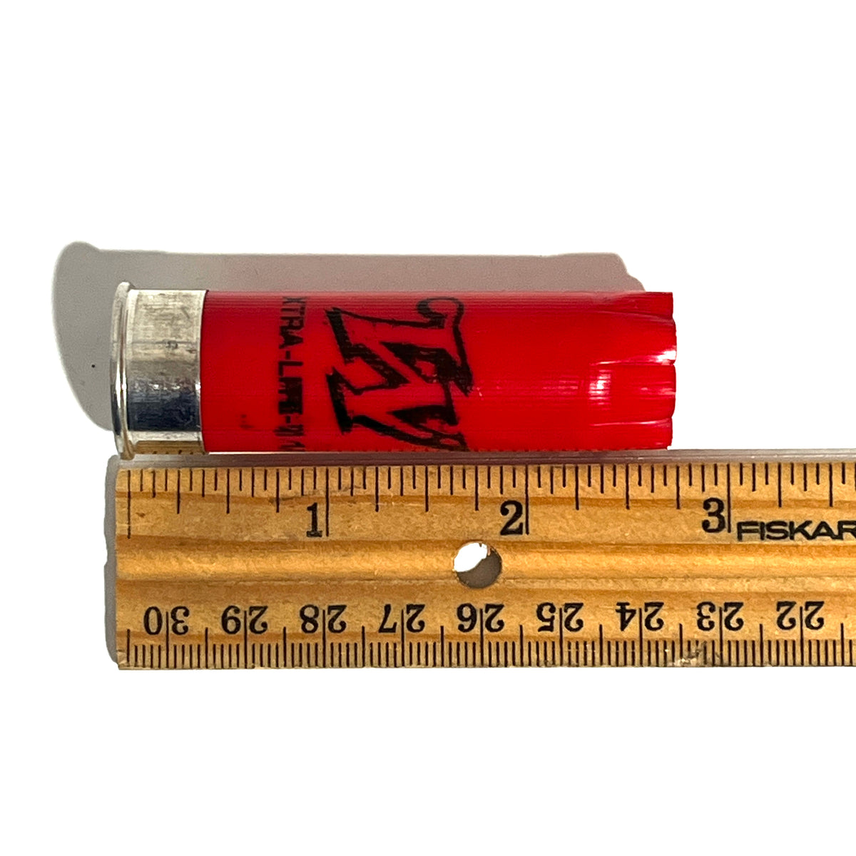 Single red Winchester 12 gauge empty shotgun shell with a silver base laid next to a wooden ruler showing a length of about 2.75 inches