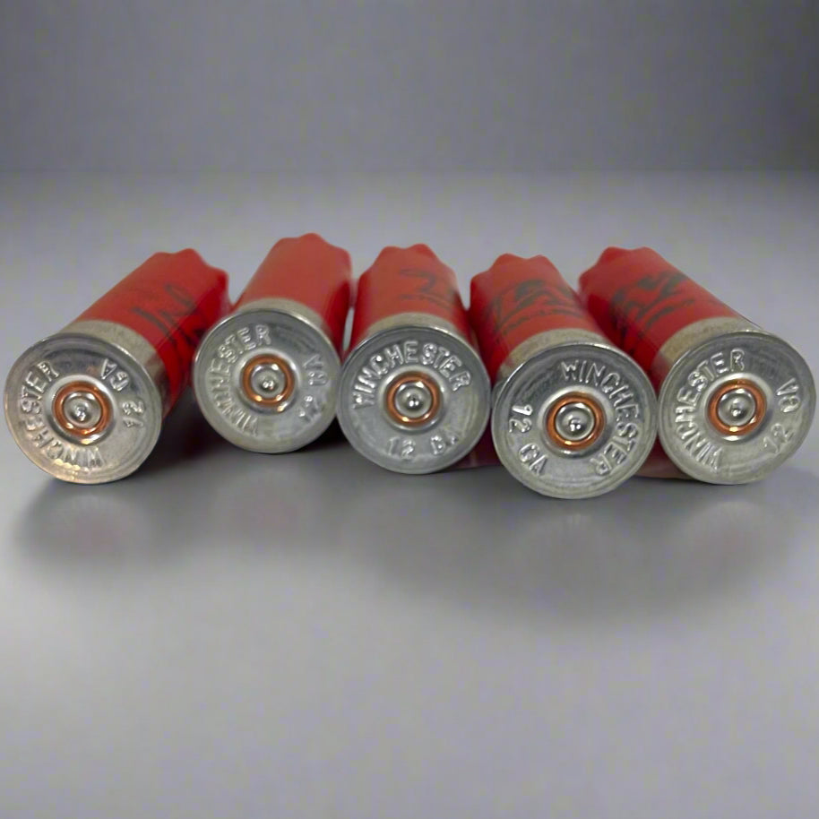Five red Winchester 12 gauge empty shotgun shells with silver bases viewed base-up on a gray background